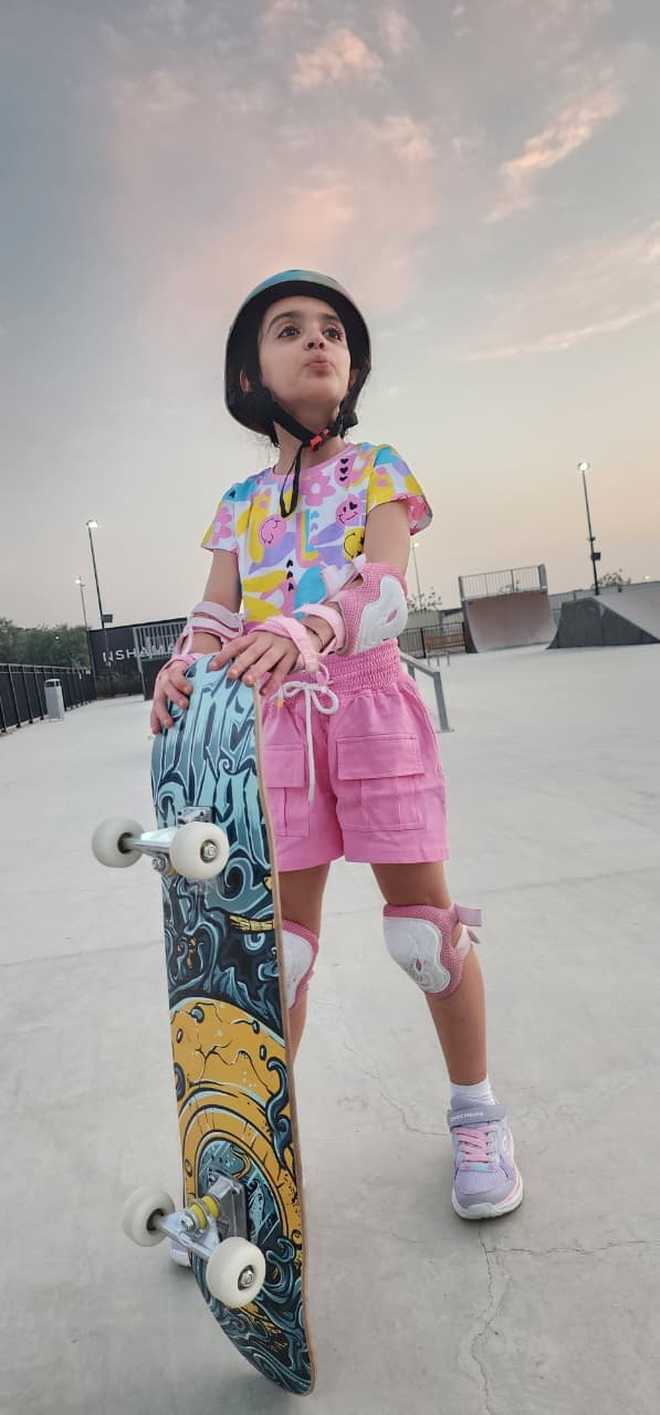 Skater standing with their board upright as the sky turns pink at dusk