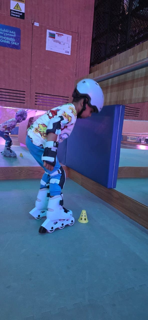 Skater in helmet and pads steadying themselves at the rink barrier